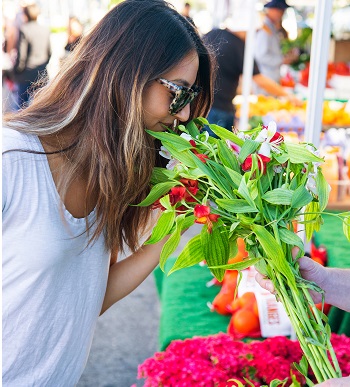 Girl smells flowers at El Segundo Farmer's Market